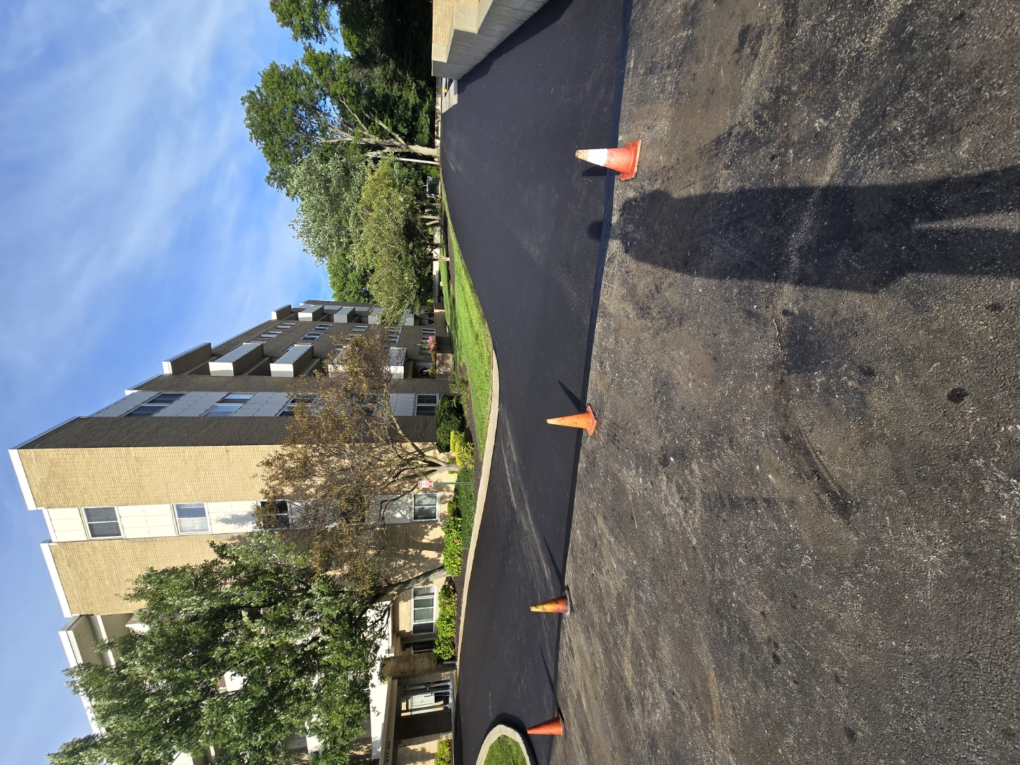 Fresh asphalt paving beside a multifamily property